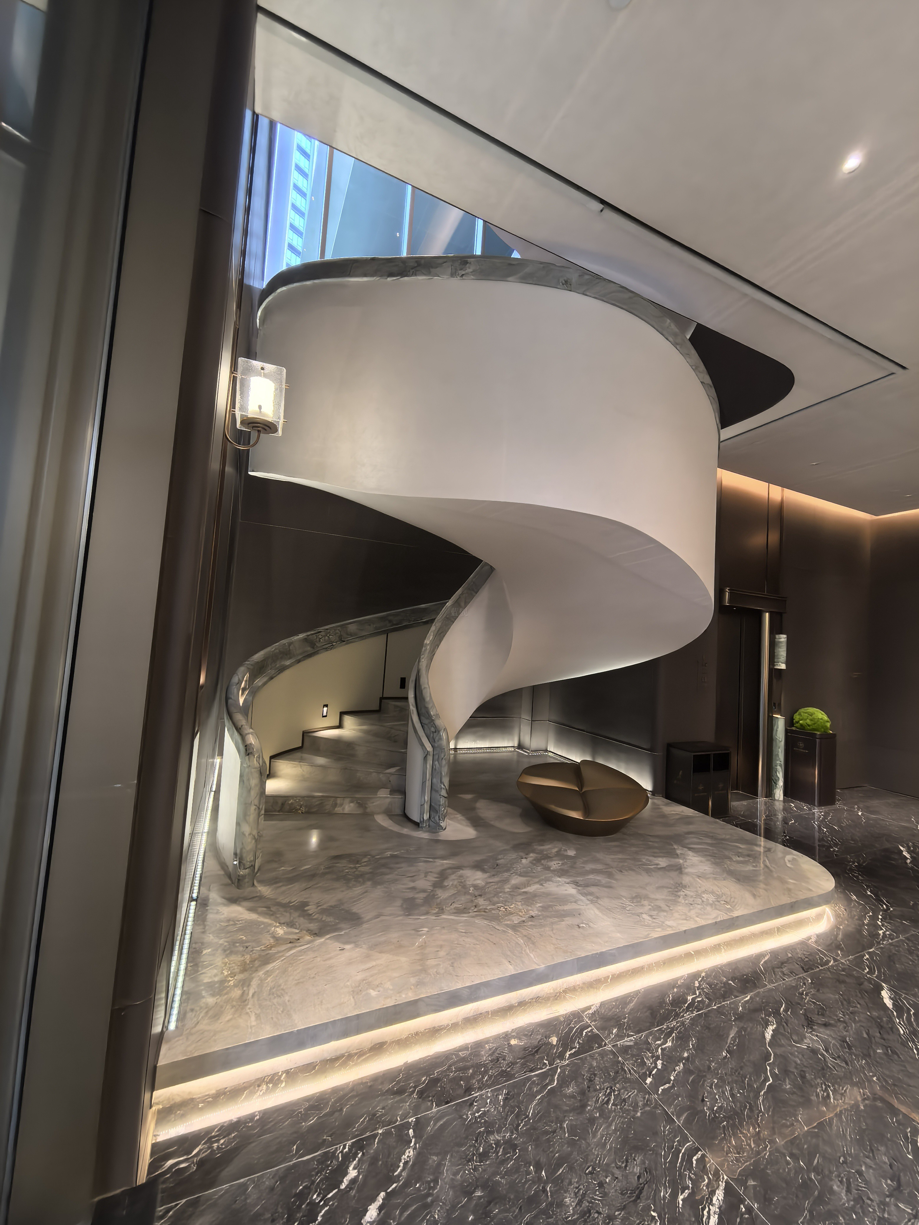 Illuminated white spiral staircase in villa lobby