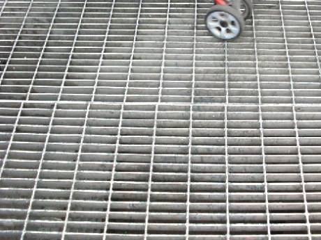 A man pushing a baby carriage through the floor made of dense steel grating..jpg