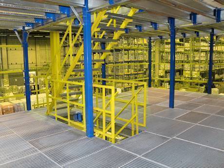 Dense steel grating used as mezzanine in a warehouse with many shelves..jpg
