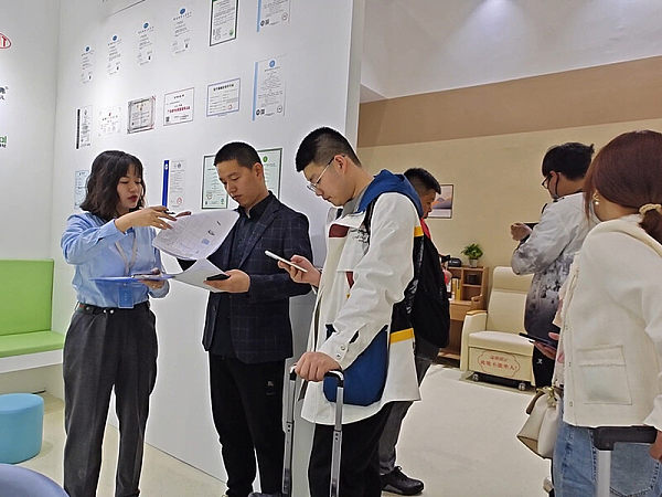 Sales answer product inquiries from visitors at the Guangzhou International Furniture Fair