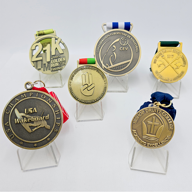 A collection of metal medals in various styles, covering events such as running, volleyball, and waterskiing. Featuring a vintage gold, silver, and bronze finish, these are collectible commemorative items for sporting events.