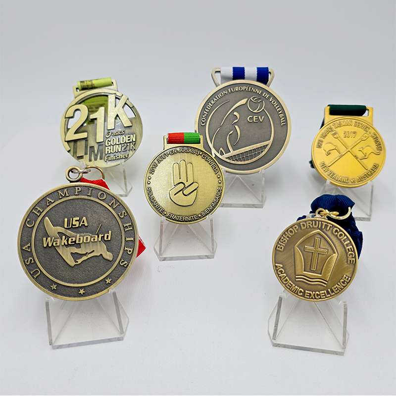 A collection of metal medals in various styles, covering events such as running, volleyball, and waterskiing. Featuring a vintage gold, silver, and bronze finish, these are collectible commemorative items for sporting events.