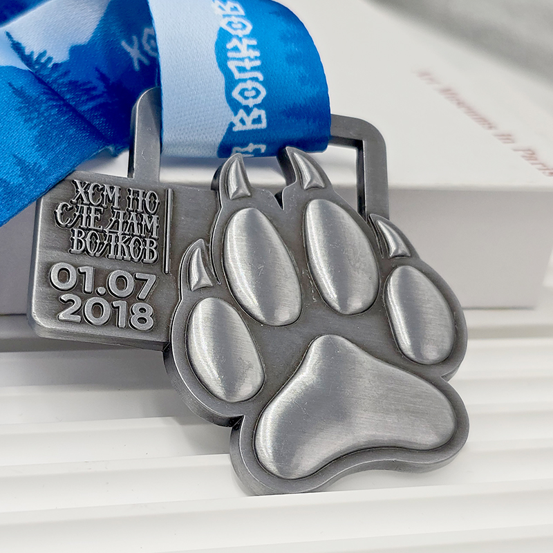 Frosted silver metal medal with bear paw design, commemorative event item, 3D paw print relief, outdoor sports collectible.