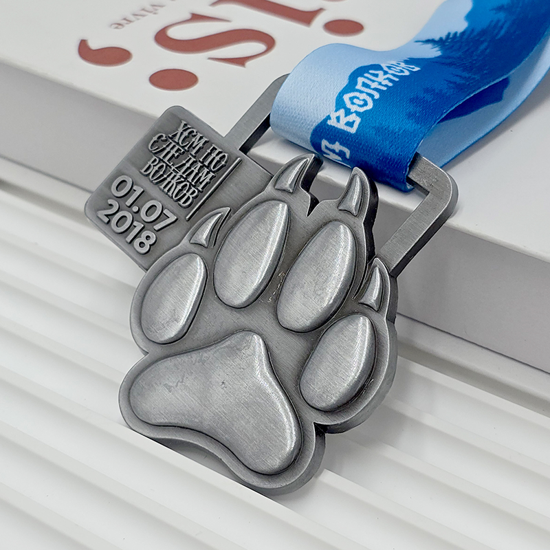 Frosted silver metal medal with bear paw design, commemorative event item, 3D paw print relief, outdoor sports collectible.