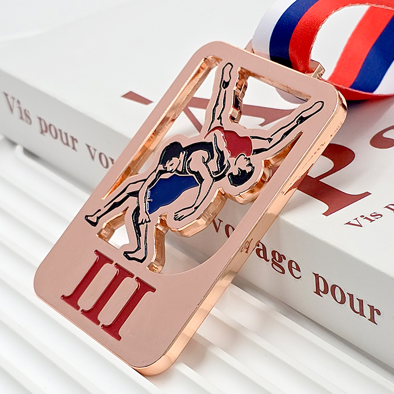 Rose gold metal medal, commemorating a bronze medal for wrestling/judo champions, featuring a 3D relief of athletes battling in action, a collectible item from a sporting event.