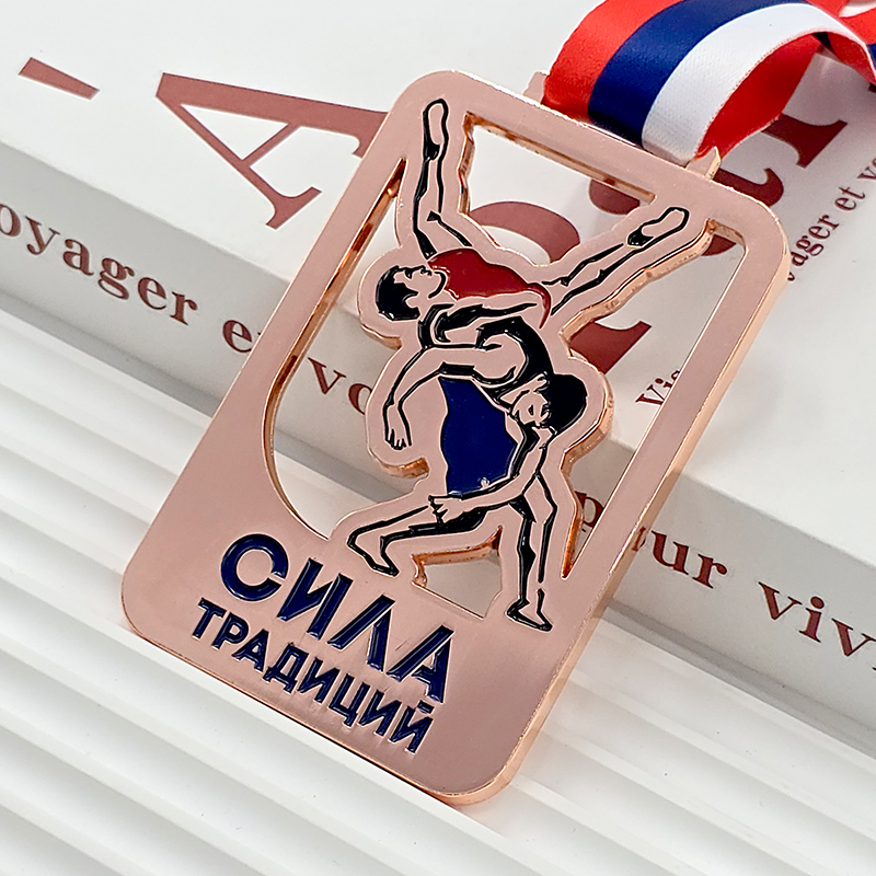 Rose gold metal medal, commemorating a bronze medal for wrestling/judo champions, featuring a 3D relief of athletes battling in action, a collectible item from a sporting event.