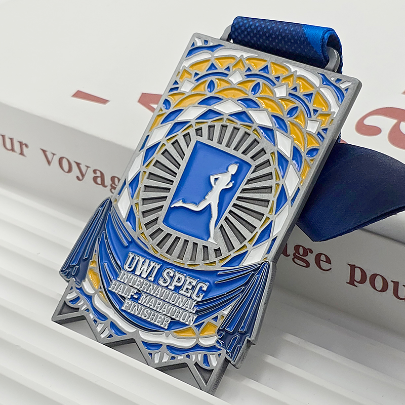 Silver, blue, and yellow color-blocked metal medal, UWI SPEC International Half Marathon finisher commemorative item, mosaic-patterned runner relief, Caribbean race collectible.