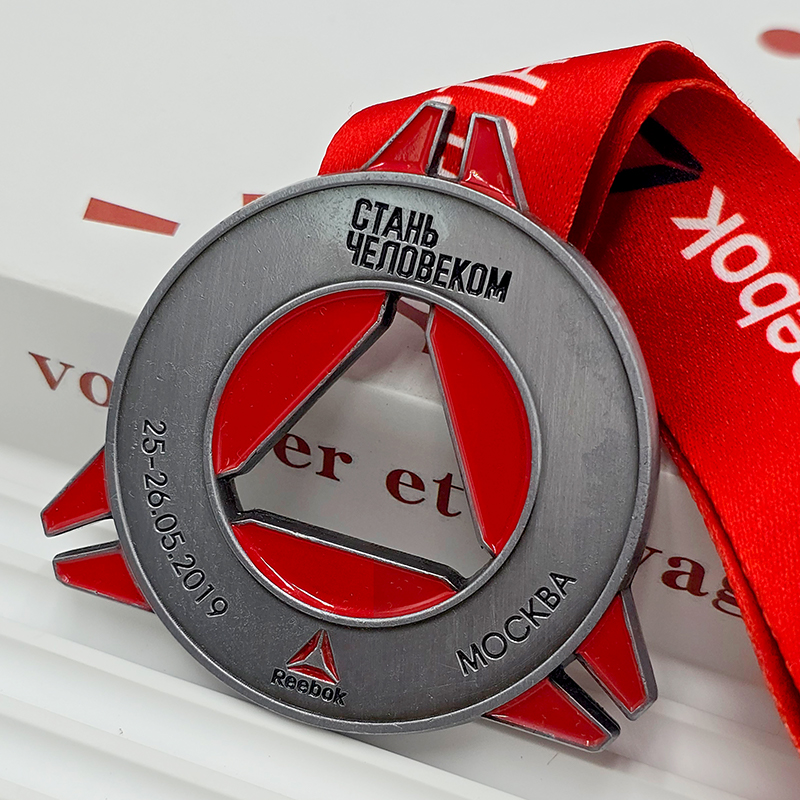 Medalla de metal en contraste plateado y rojo, anillo conmemorativo de la carrera Reebok de Moscú con relieve calado triangular en forma de anillo, artículo coleccionable de eventos deportivos.