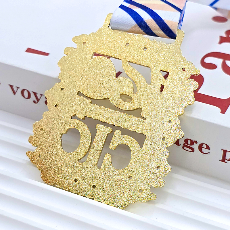 Medallas metálicas con bloques de color dorado y azul, artículos conmemorativos de eventos deportivos, motivos florales de estilo retro, letras, relieves en 3D, objetos de colección de eventos deportivos.