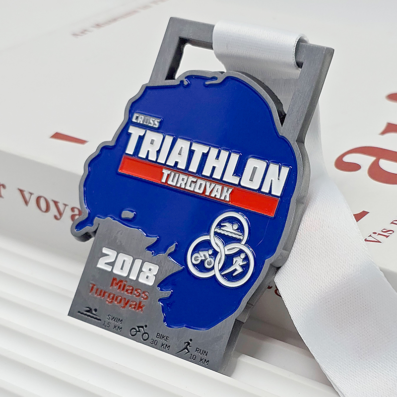 Medalla metálica bicolor plateada y azul, conmemorativa del Triatlón Turgoyak 2018, con un relieve en 3D del contorno de un lago, un artículo coleccionable de un evento deportivo al aire libre ruso.