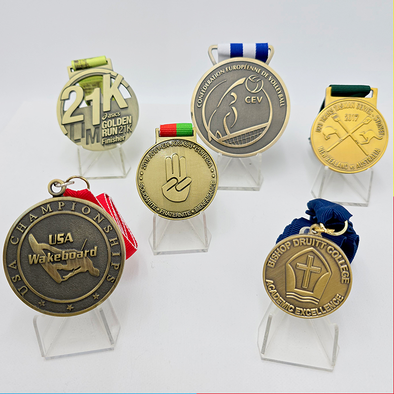 Eine Sammlung von Metallmedaillen in verschiedenen Stilen, die Veranstaltungen wie Laufen, Volleyball und Wasserski abdecken. Mit einem Vintage-Gold-, Silber- und Bronze-Finish sind dies sammelbare Erinnerungsstücke für Sportveranstaltungen.