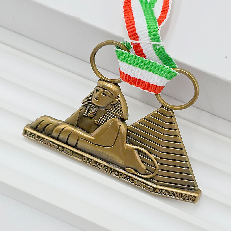 Antike Bronzemedaille mit Relief der ägyptischen Sphinx-Pyramide; italienisches Trikolorenband als Gedenkornament; exotisches kulturelles Sammlerabzeichen.