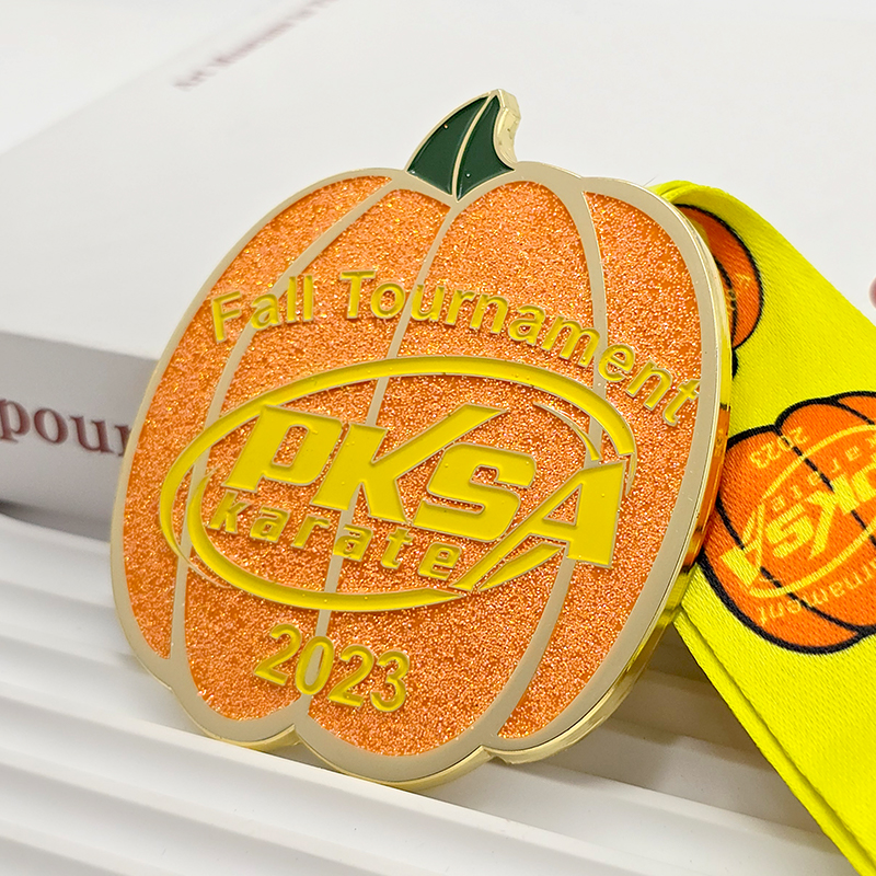 Orange-goldene Metallmedaille in Kürbisform mit Farbblockdesign, zur Erinnerung an die PKSA Karate-Herbstmeisterschaften 2023, Sammlerstück zum Thema Halloween.