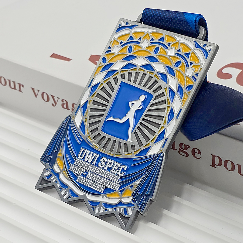 Silberne, blaue und gelbe Metallmedaille mit Farbblockdesign, Erinnerungsstück für Finisher des UWI SPEC International Half Marathon, Relief mit Mosaikmuster, Sammlerstück für Karibik-Läufe.