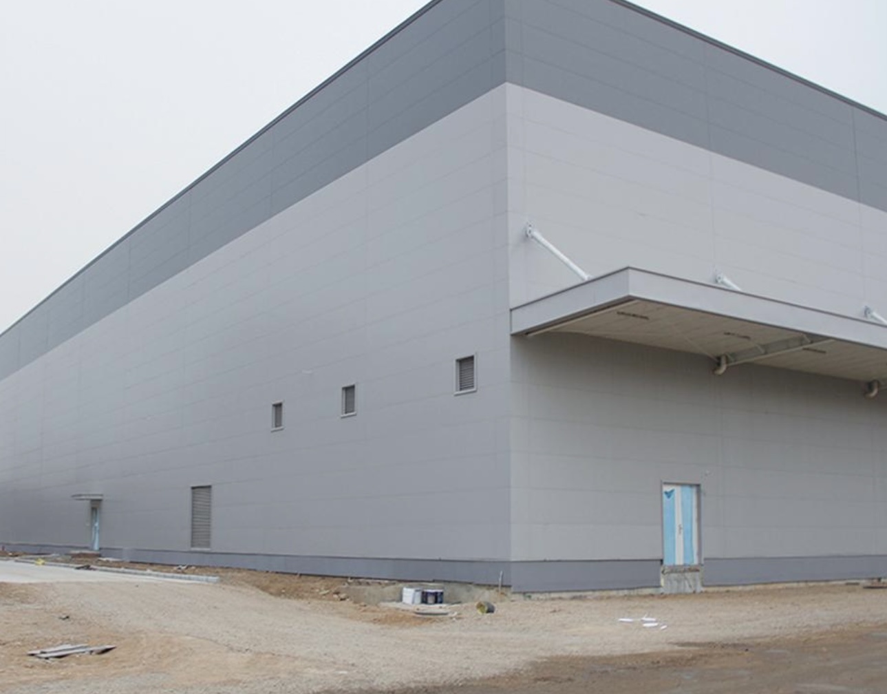 Modern multi-story factory building with non-standard styling and colored steel cladding.