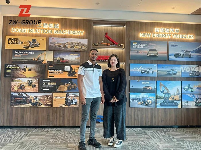 African client group photo in ZW Group showroom: inspecting semi-trailers, dump trucks, and specialized transport solutions.