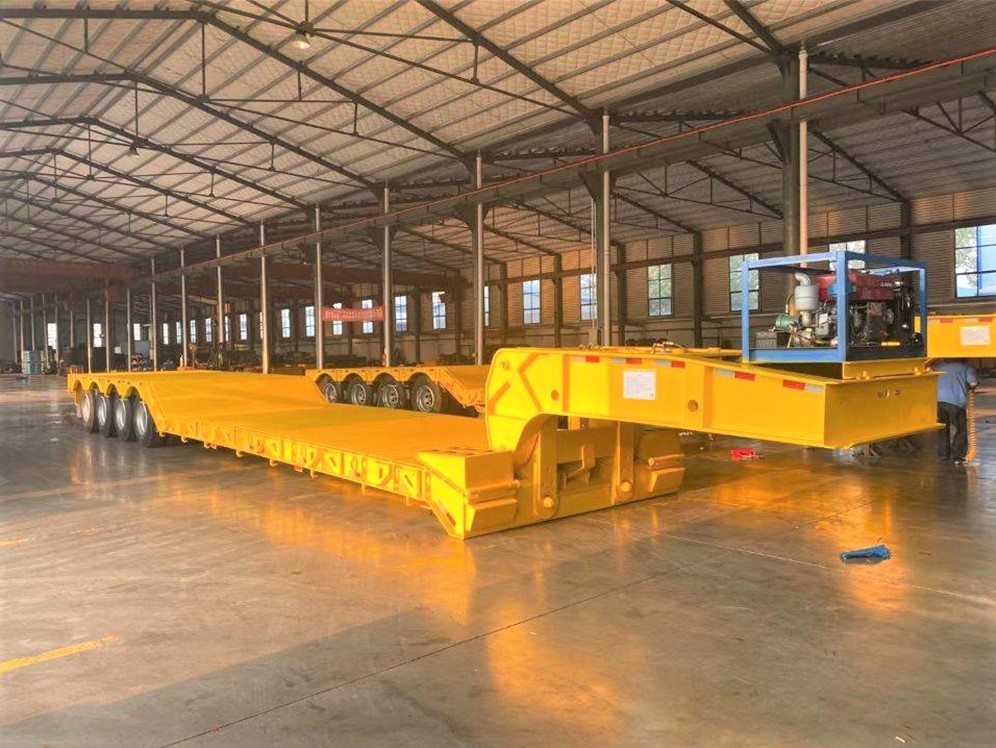 4 axle 100 ton RGN lowboy trailer front three quarter view highlighting low deck height and heavy-duty axle layout