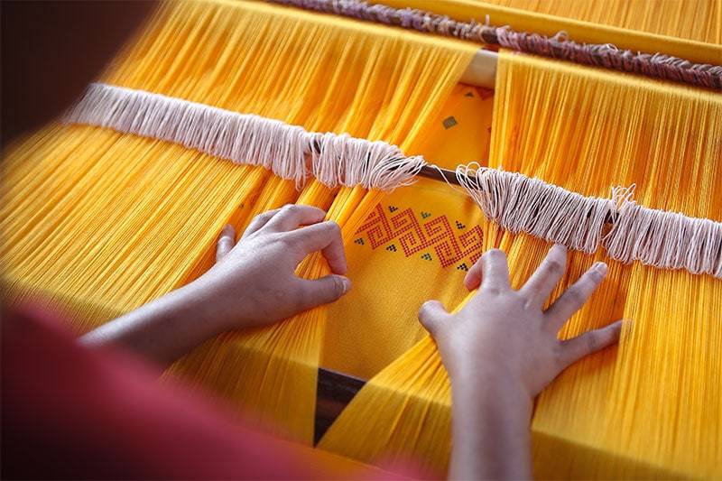 woman weaving with organic cotton woman weaving with organic cotton