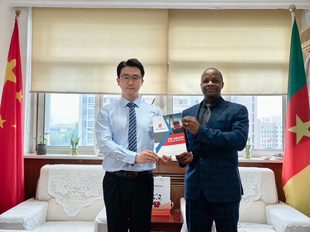ZW Group Manager Kiyya Zhang with Cameroon official Etoua Julien Freddy showcasing the heavy truck and trailer supply catalog.