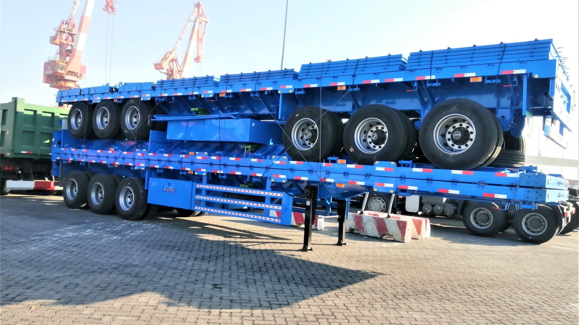 Entrega portuária de semirreboques plataforma do ZW Group: logística de exportação profissional e transporte terrestre para pedidos internacionais de equipamentos pesados.