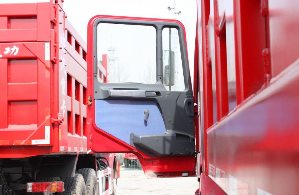 Shacman F2000 6x4 dump truck driver side door detail showing handle, cabin access, and reinforced construction