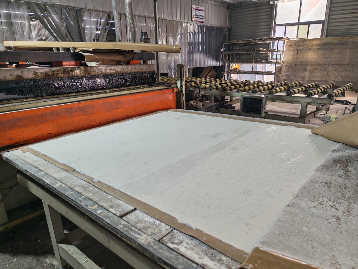 Standard and jumbo quartz slab sizes stacked upright on A-frame racks inside an engineered quartz slab factory warehouse