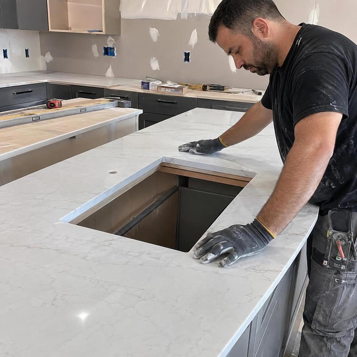 Installer fitting an undermount sink into an engineered quartz countertop Installer fitting an undermount sink into an engineered quartz countertop