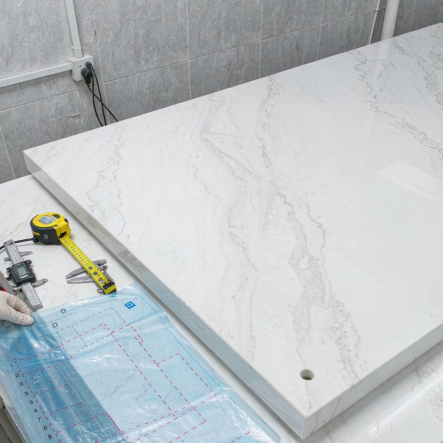 Technician checking a custom cut quartz slab against an installation template
