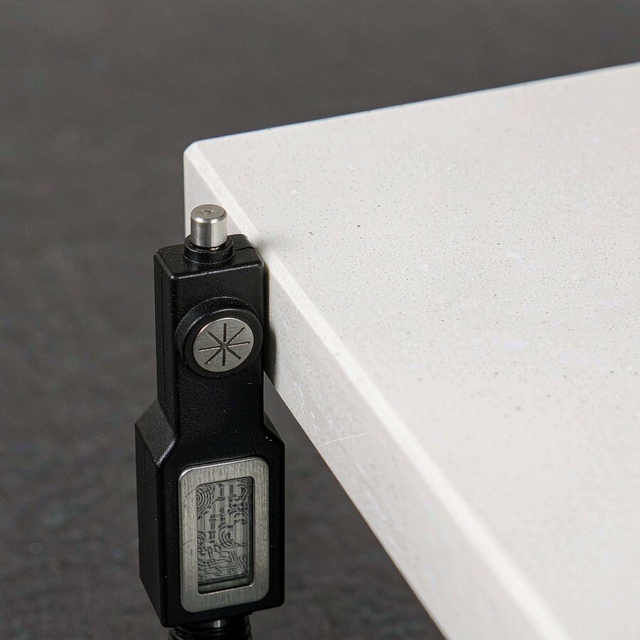 Digital thickness gauge measuring a quartz slab to verify it matches the ordered specification within tolerance