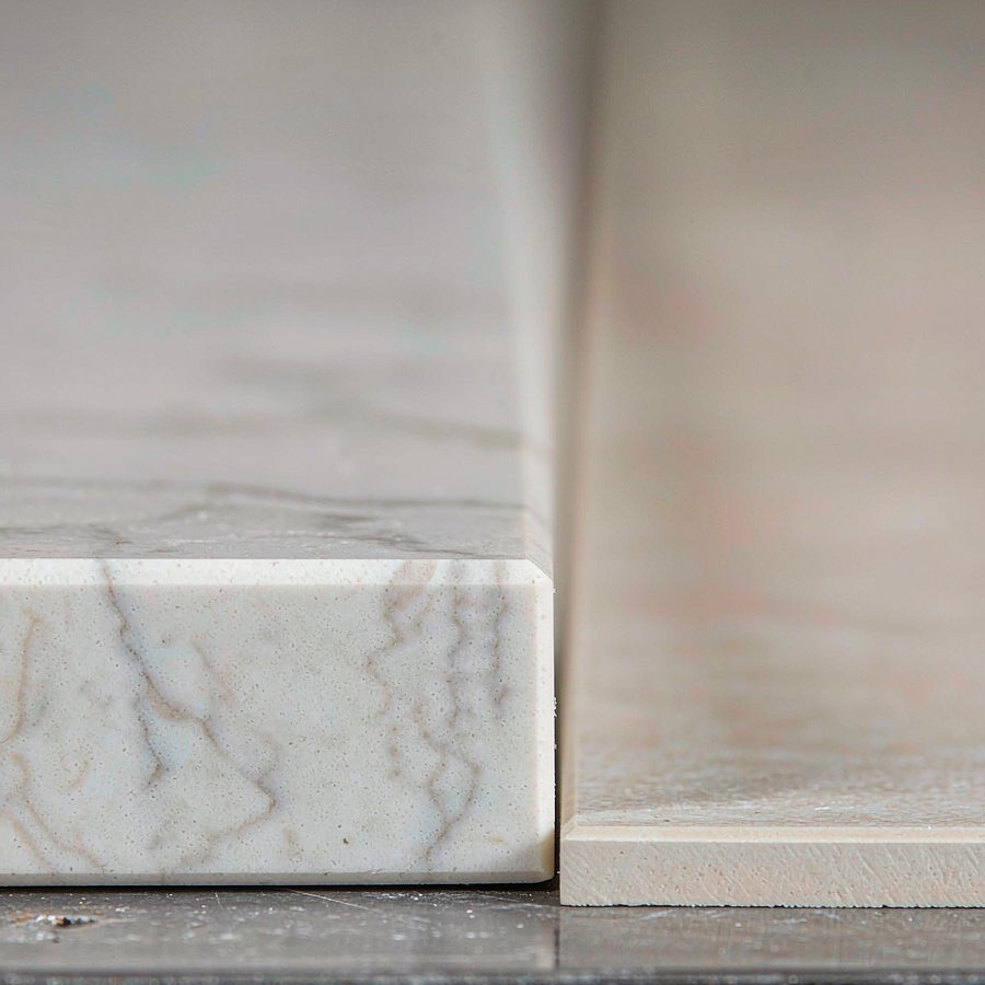 Close-up of a 20 mm polished engineered quartz slab edge beside a thin porcelain slab edge, showing body thickness