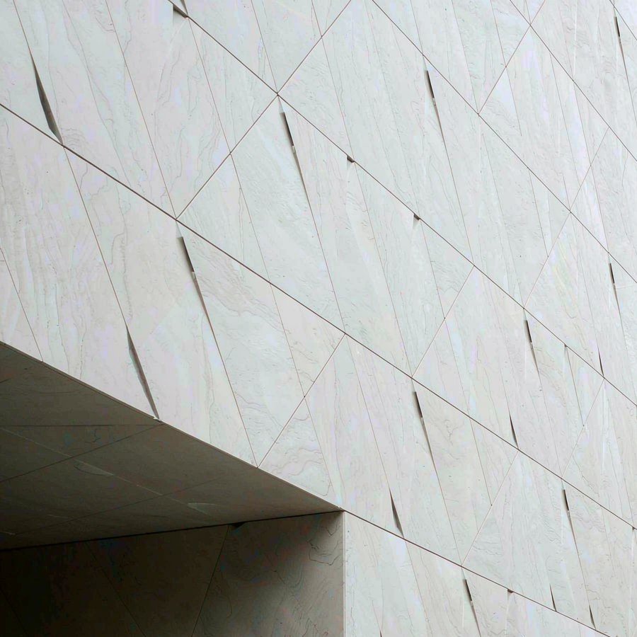Large porcelain panels installed on a commercial facade shown beside a polished quartz slab sample
