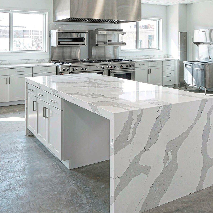 Polished engineered quartz island worktop installed in an empty modern commercial kitchen with no people
